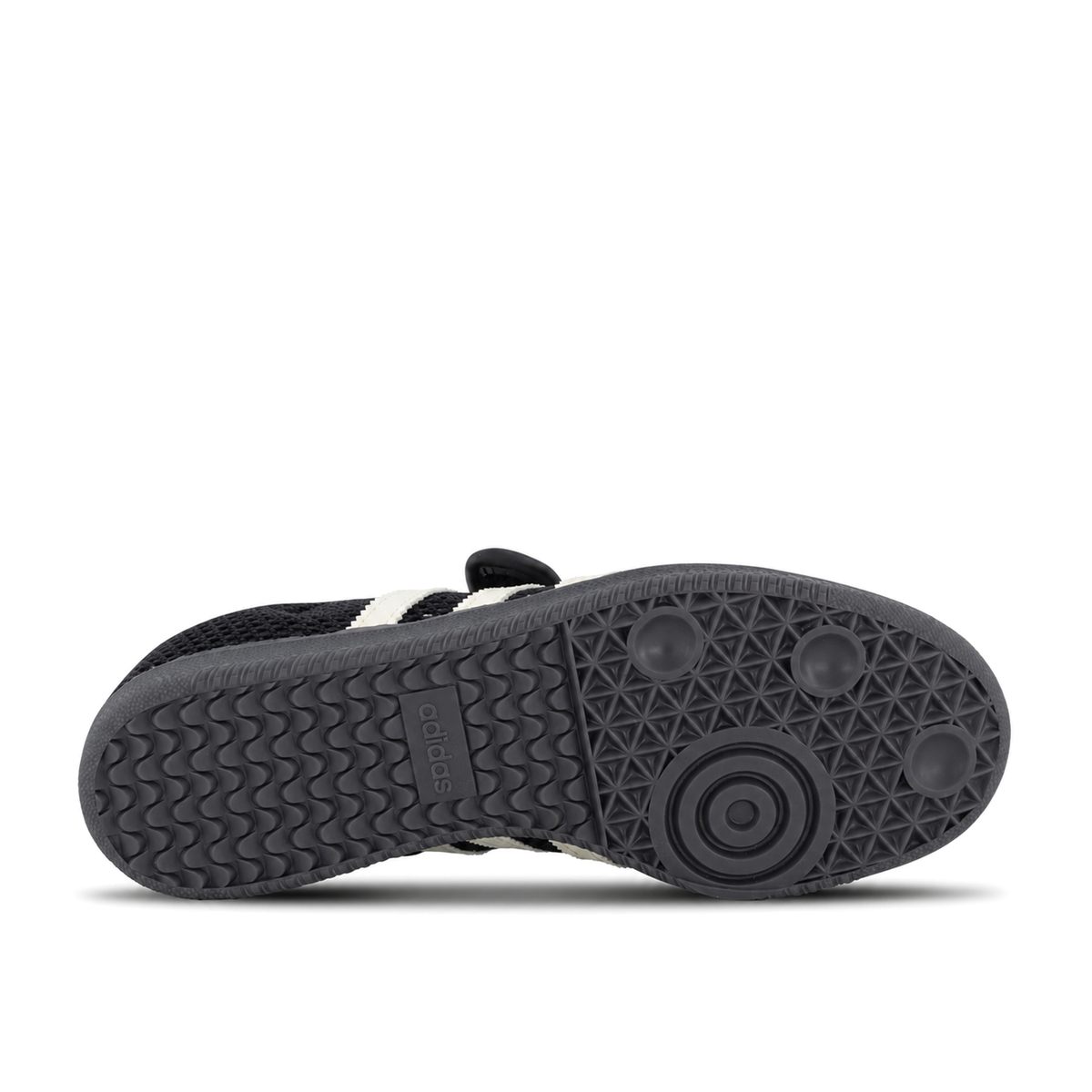Horizontal dark outsole of adidas Originals Samba Jane Core Black Off White Gold with wavy heel tread on the left and circular forefoot tread on the right