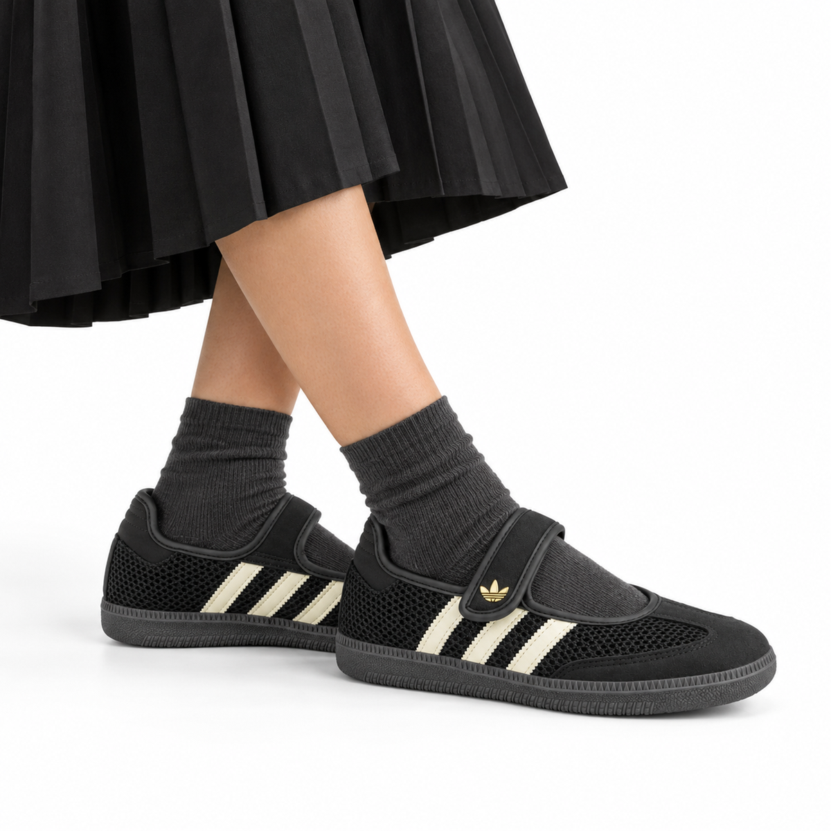 adidas Originals Samba Jane – Core Black / Off White / Gold worn with a black pleated midi skirt with charcoal ankle socks, both shoes facing right