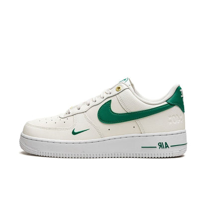 A pair of Nike Air Force 1 'Malachite White' sneakers with a classic white tumbled leather upper and green detailing.